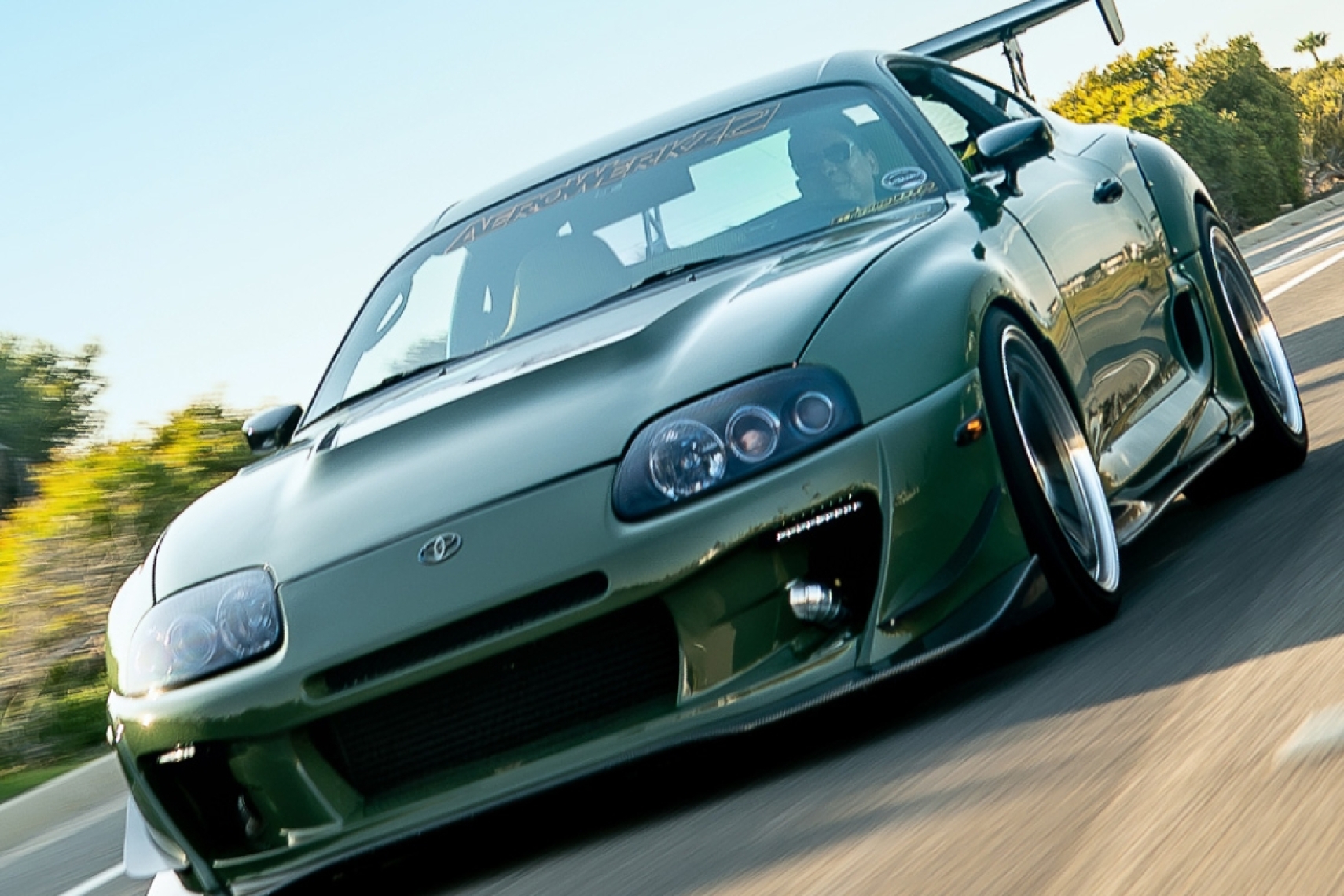 Leopold Barrit’s Military Olive Green 1995 Toyota Supra rolling on the street with Varis widebody styling and Advan wheels.